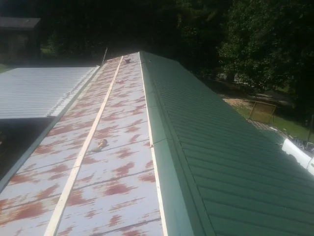 Old rusted panels beside newly installed green metal roofing — Wind Damage Roof Repair by Roofing Brothers in Norborne