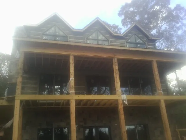 Dormers and porch framing on a large log home under construction — Roof Coating work by our crew in Norborne