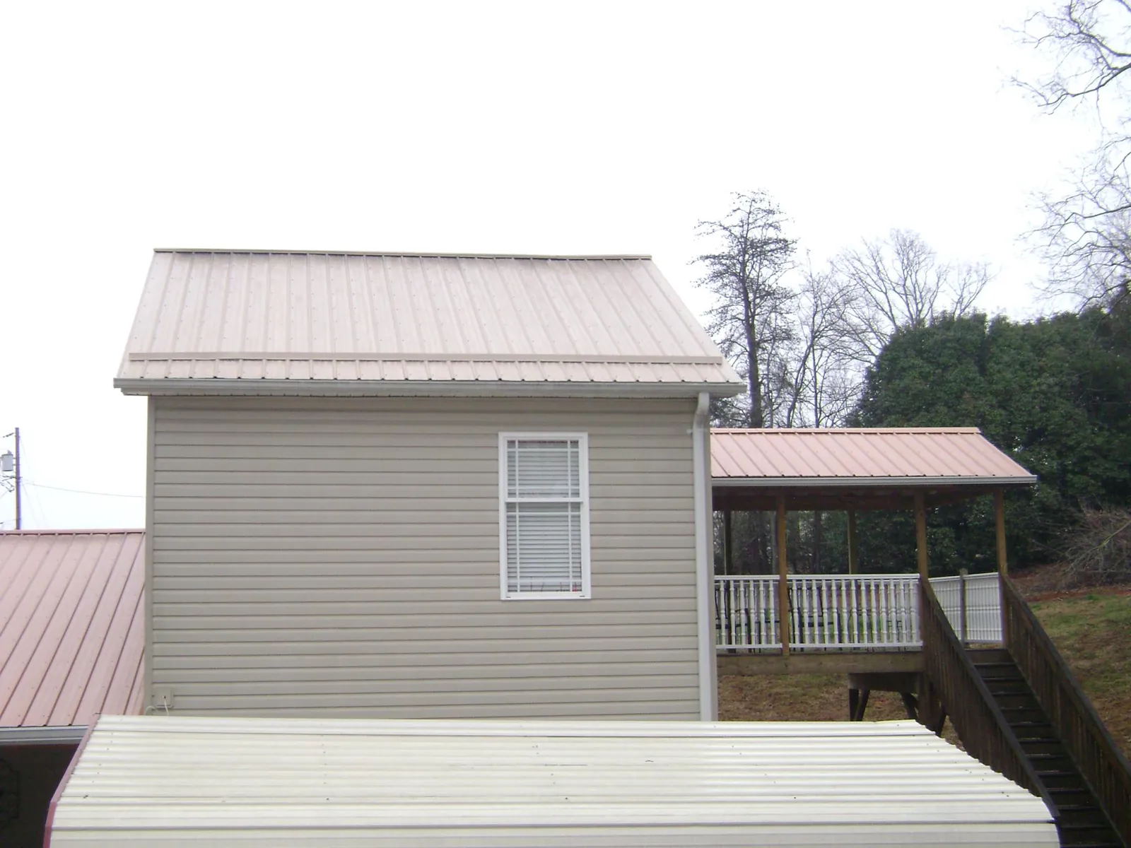 Tan metal roofs on a two story addition and attached porch, from a Roof Replacement job in Norborne