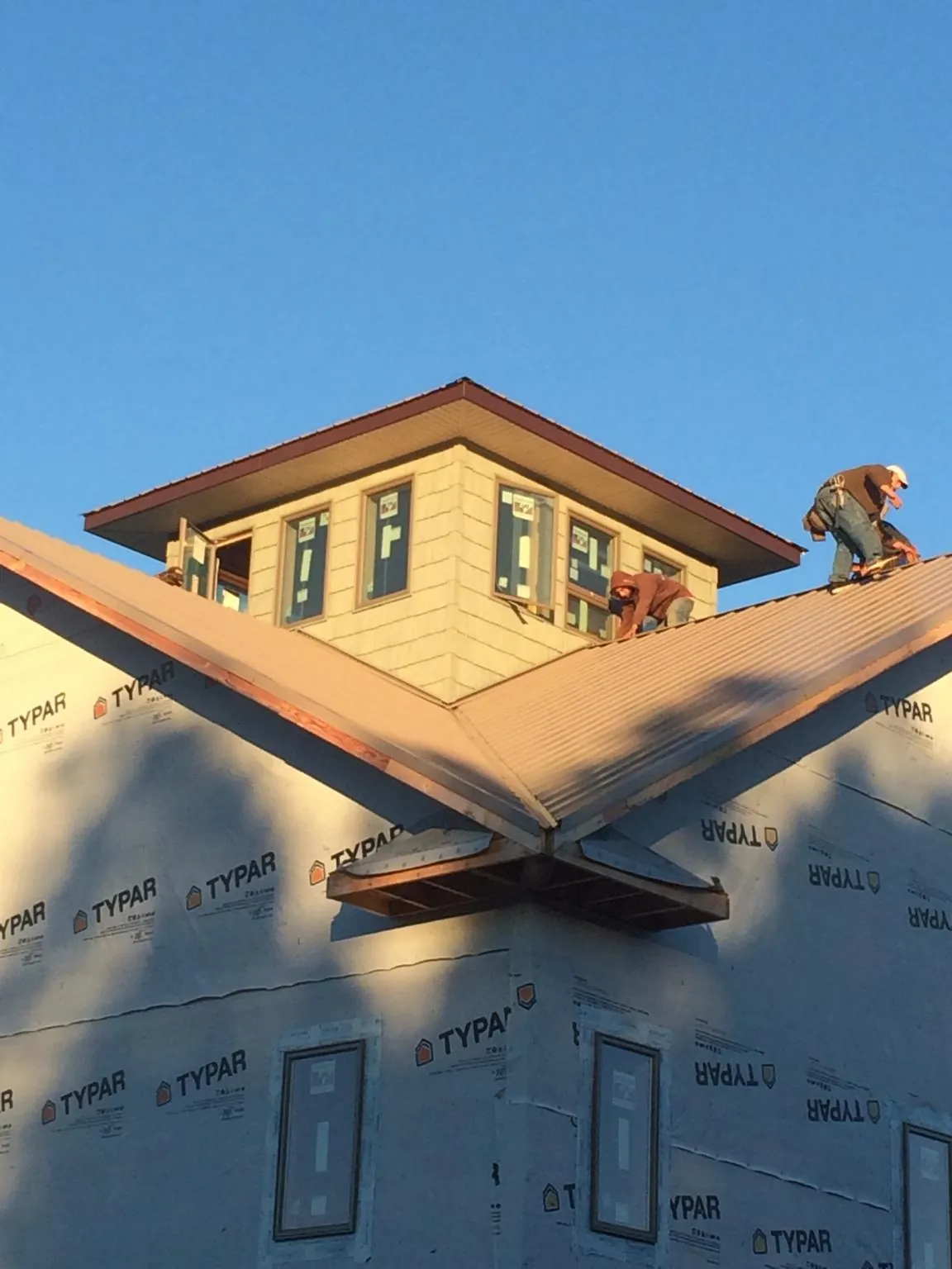 Roofers working around a rooftop cupola on a new metal roof at sunset — Roof Waterproofing in Norborne by Roofing Brothers